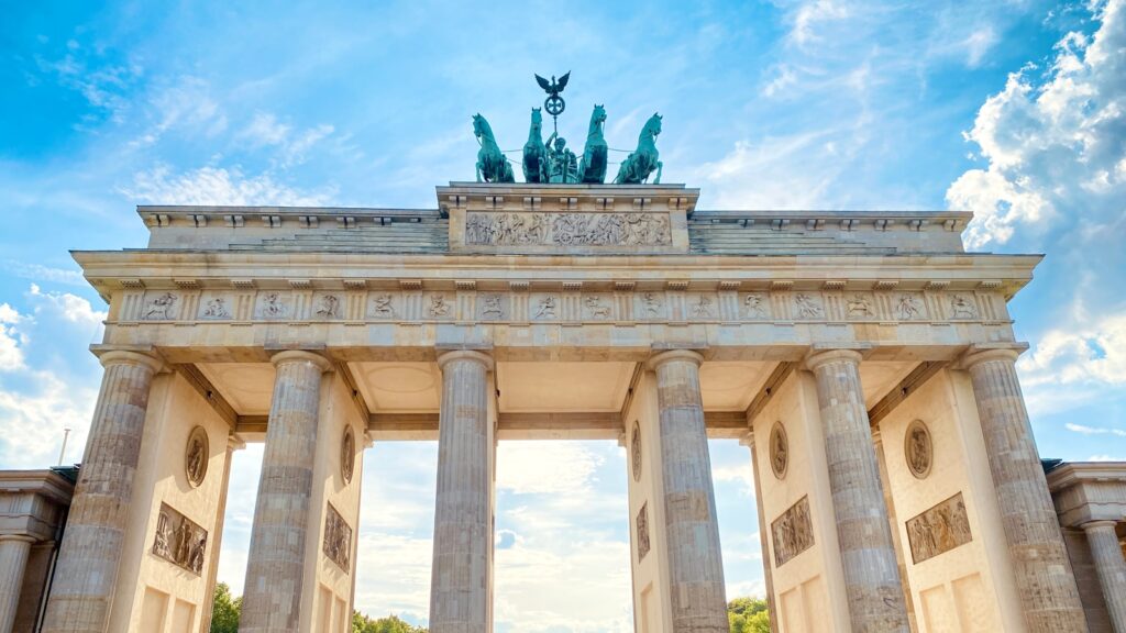 Berlin in 3 Days - a large stone building with columns and statues on top with Brandenburg Gate in the background